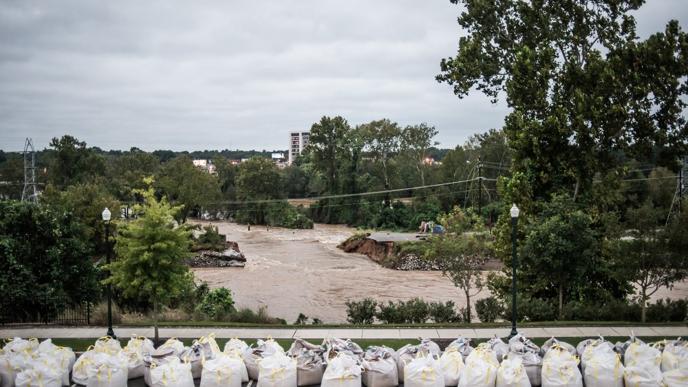 Flood waters rush through the breach of the Columbia Canal as emergency workers prepare giant sandbags to plug the hole on Oct. 5, 2015 in Columbia, S.C. (Photo by Sean Rayford/Getty)