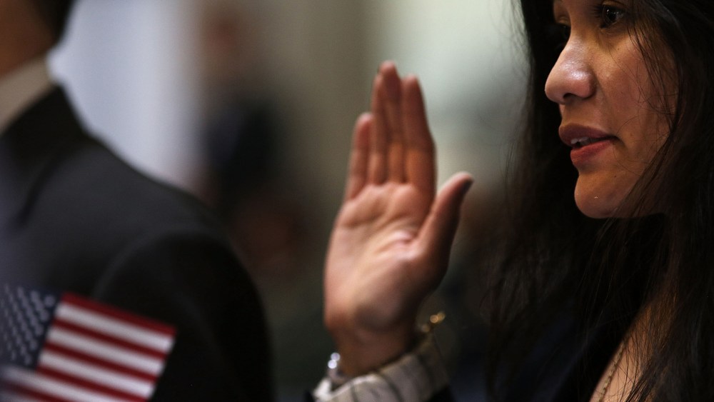 People hold up their right hands during a naturalization ceremony at Federal Hall for approximately 75 citizenship candidates from 31 countries on May 22, 2014 in New York City.