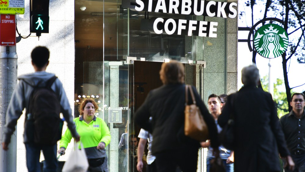 Pedestrians cross a street in front of a Starbucks coffee house in Sydney on May 28, 2014.
