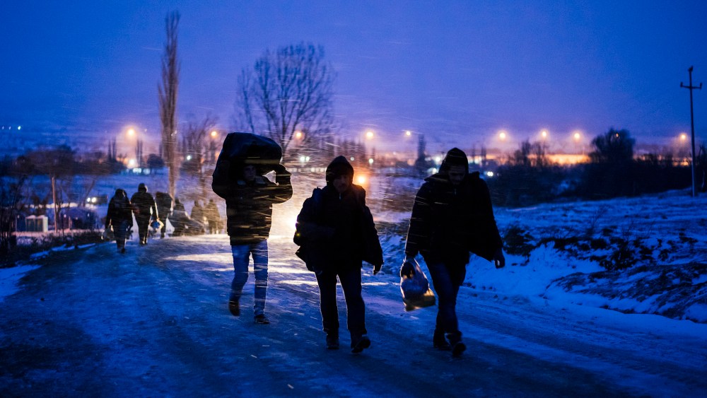 Migrants and refugees walk on a snow covered street after crossing the Macedonian border into Serbia near the village of Miratovac on Jan. 17, 2016. (Photo by Dimitar Dilkoff/AFP/Getty)