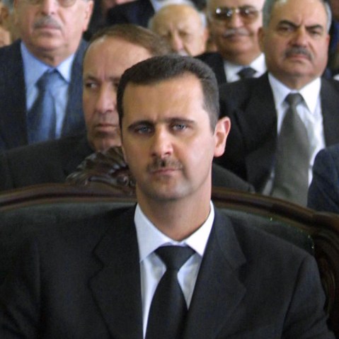 File Photo: Syrian President Bashar al-Assad (C) attends a ceremony marking the one-year anniversary his father's death in the northern city of Qerdaha 10 June 2001. (Photo by Louai Beshara/AFP/Getty Images File)