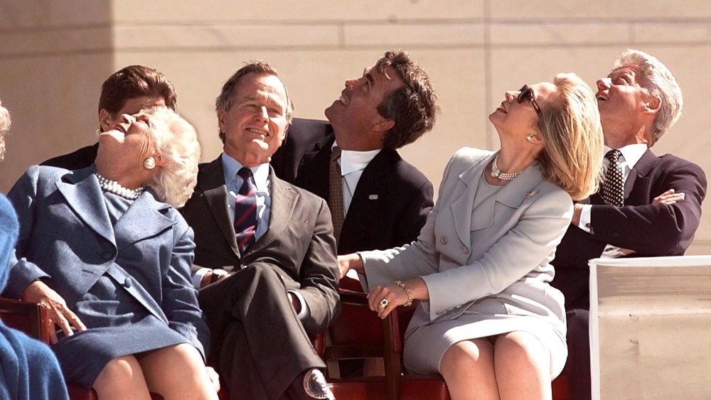In less competitive times, George Bush, Barbara Bush and Jeb Bush, sit with First Lady Hillary Clinton and President Bill Clinton, watching US Army parachuters at the dedication of the George Bush Library in TX. (Photo by Joyce Naltchayan/AFP/Getty)