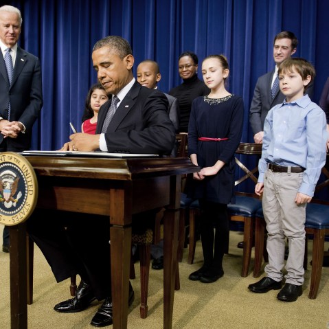 US President Barack Obama (C) signs executive orders with Vice President Joe Biden (L) and invited guests during an event unveiling a package of proposals to reduce gun violence at the White House in Washington, DC, January 16, 2013. Obama signed 23...