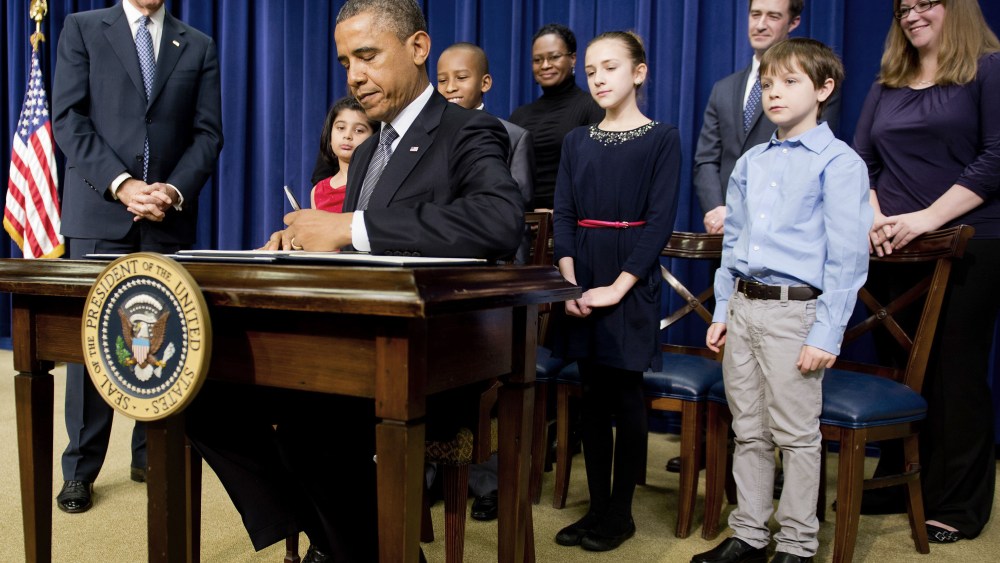 US President Barack Obama (C) signs executive orders with Vice President Joe Biden (L) and invited guests during an event unveiling a package of proposals to reduce gun violence at the White House in Washington, DC, January 16, 2013. Obama signed 23...