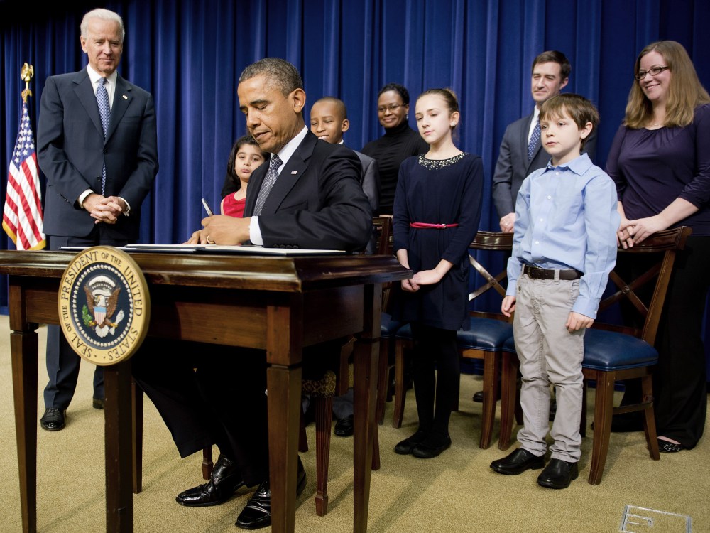 US President Barack Obama (C) signs executive orders with Vice President Joe Biden (L) and invited guests during an event unveiling a package of proposals to reduce gun violence at the White House in Washington, DC, January 16, 2013. Obama signed 23...