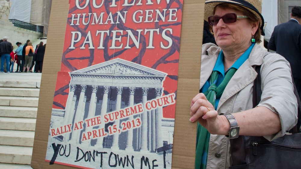 A woman holds a banner demanding a ban over human genes patents during a protest outside the US Supreme Court in Washington on April 15, 2013. The Supreme Court is poised to take up the highly charged question of whether human genes can be patented. ...