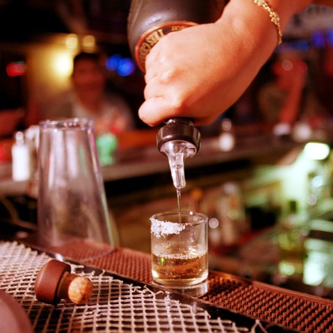 A shot of tequila is poured at a bar.