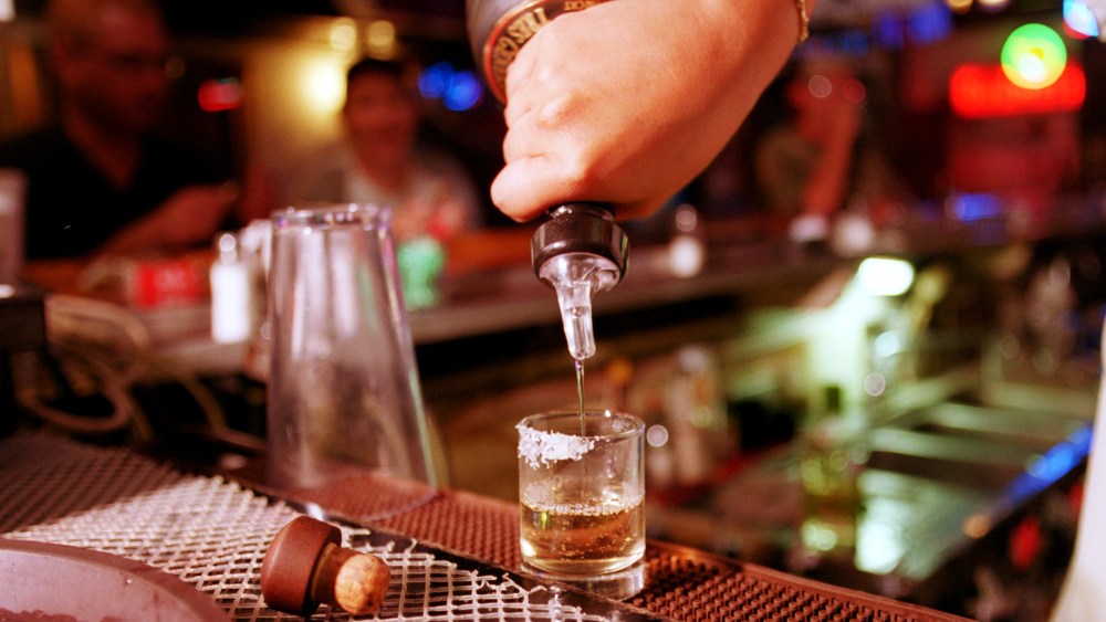 A shot of tequila is poured at a bar.