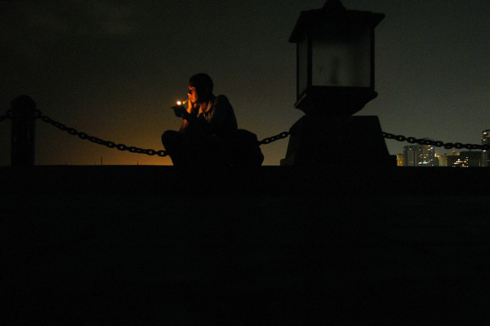 A man lights a cigarette at a seaside park in Manila, Philippines.