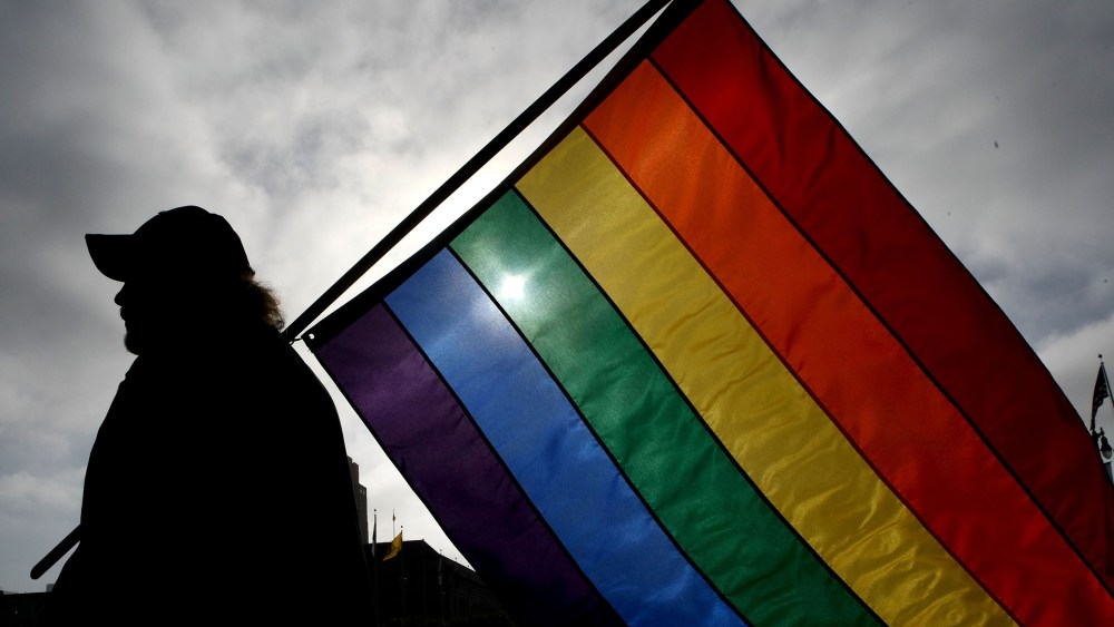A man holds a gay pride flag.