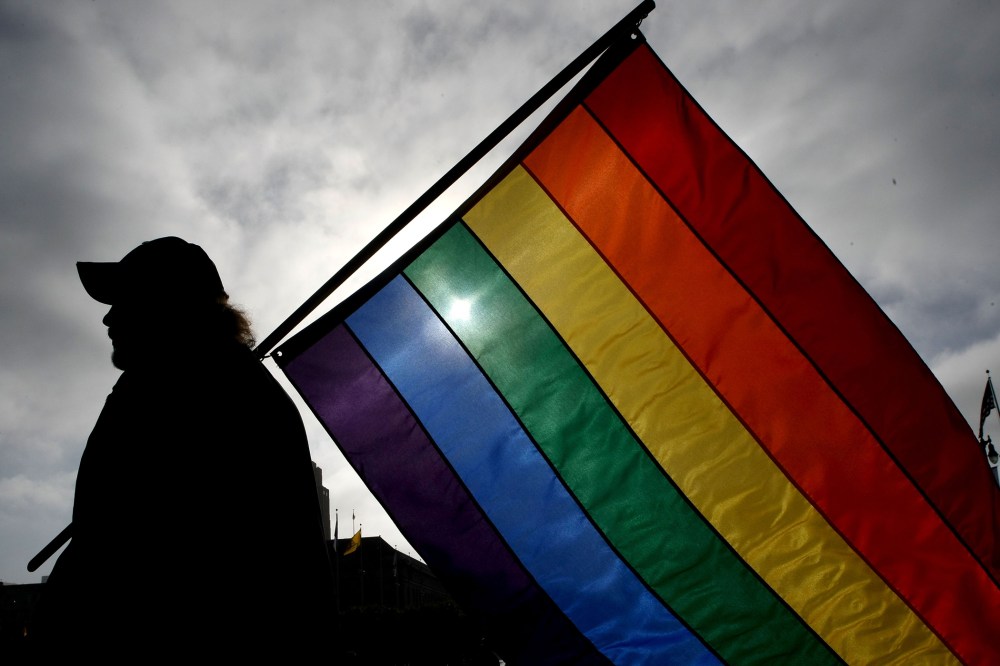 A man holds a gay pride flag.