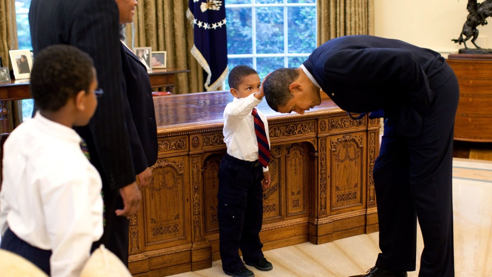 File Photo: In this handout from the The White House, U.S. President Barack Obama bends over so the son of a White House staff member can pat his head during a visit to the Oval Office May 8, 2009 in Washington, DC.  (Photo by Pete Souza/The White...