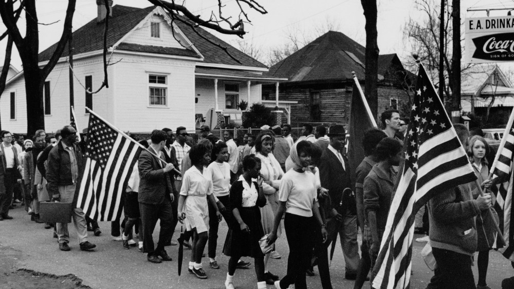 Circa 1965:  Participants, some carrying American flags, marching in the civil rights march from Selma to Montgomery, Alabama in 1965  (Photo by Buyenlarge/Getty Images, File)