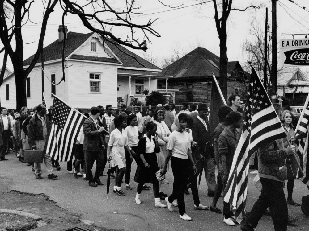 Circa 1965: Participants, some carrying American flags, marching in the civil rights march from Selma to Montgomery, Alabama in 1965 (Photo by Buyenlarge/Getty Images, File)