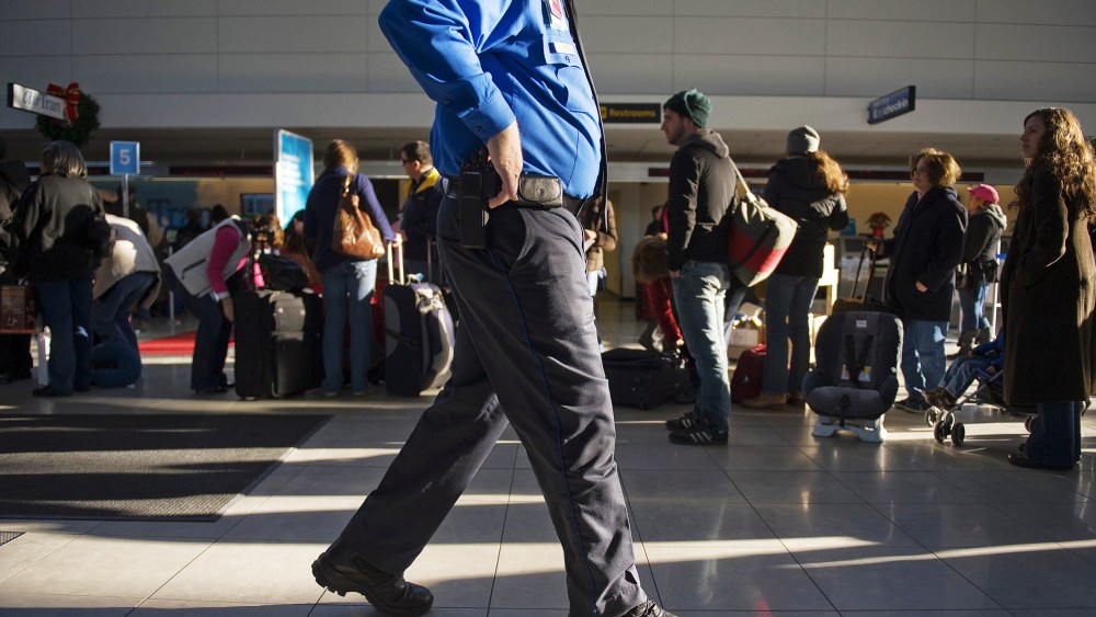 A Transportation Security Administration official walks by passengers at the Baltimore Washington International Airport. (Photo by Jim Watson/AFP/Getty)