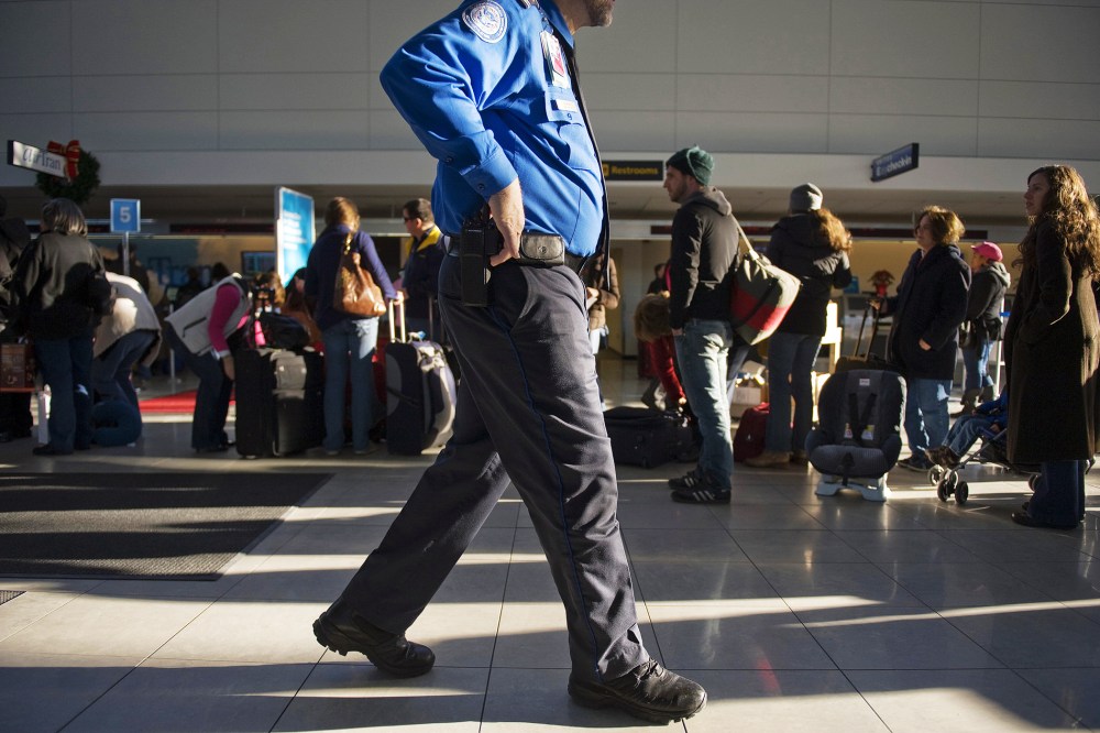A Transportation Security Administration official walks by passengers at the Baltimore Washington International Airport. (Photo by Jim Watson/AFP/Getty)