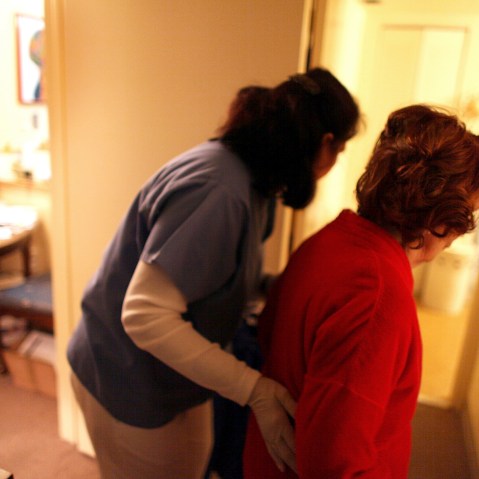 Home health aide Wendy Cerrato (L) helps a client in her apartment to bath and dress on January 6, 2010 in Miami, Fla.