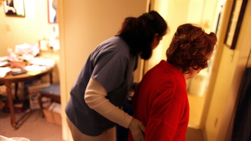 Home health aide Wendy Cerrato (L) helps a client in her apartment to bath and dress on January 6, 2010 in Miami, Fla.