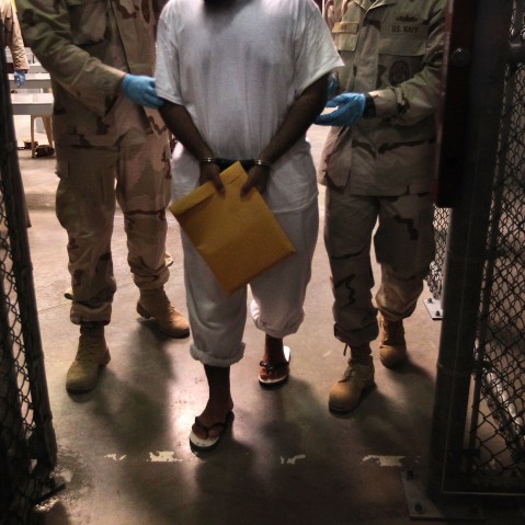 File Photo:  U.S. Navy guards escort a detainee after a "life skills" class at Camp 6 in the Guantanamo Bay detention center on March 30, 2010 (Photo by John Moore/Getty Images, File)