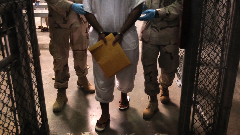 File Photo:  U.S. Navy guards escort a detainee after a "life skills" class at Camp 6 in the Guantanamo Bay detention center on March 30, 2010 (Photo by John Moore/Getty Images, File)