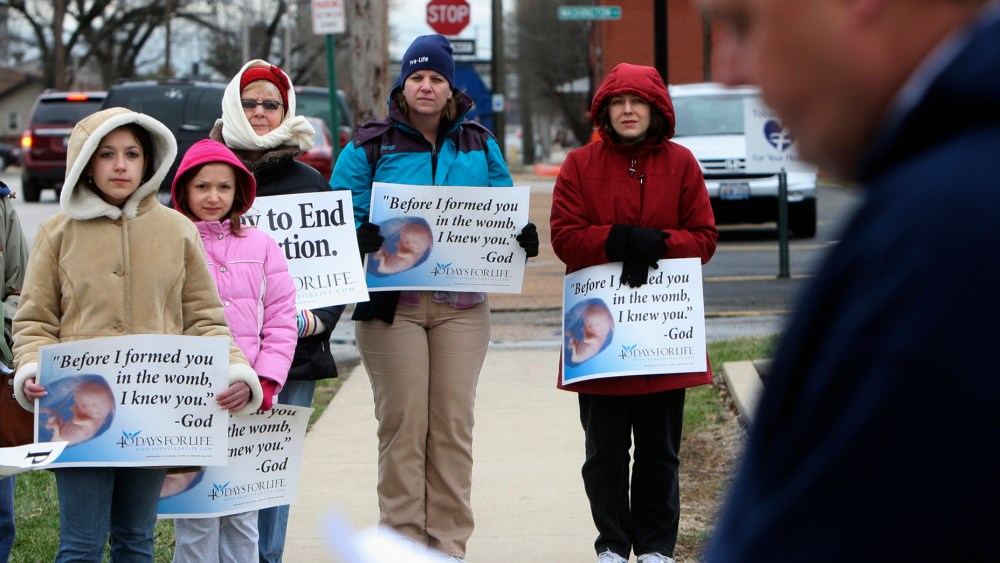 In this March 8, 2011, file photo, anti-abortion protesters gather outside the Hope Clinic for Women in Granite City, Ill., as Rev. Chris Comerford, right, from St. Elizabeth's Catholic Church in Granite City speaks out against the abortion clinic.  ...