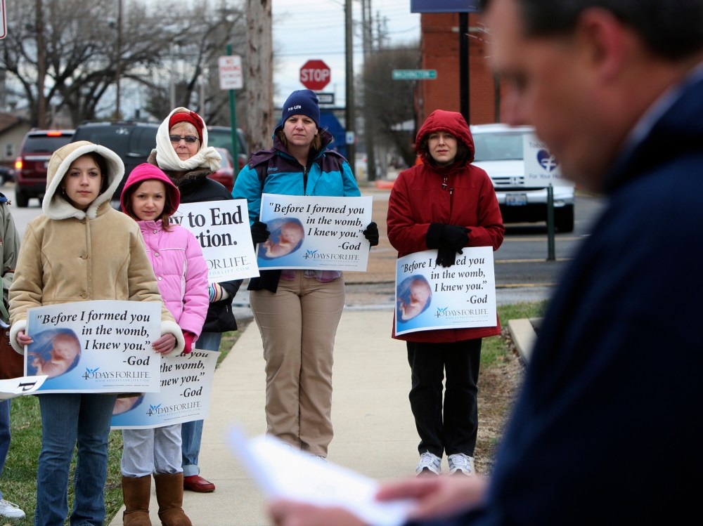 In this March 8, 2011, file photo, anti-abortion protesters gather outside the Hope Clinic for Women in Granite City, Ill., as Rev. Chris Comerford, right, from St. Elizabeth's Catholic Church in Granite City speaks out against the abortion clinic. ...