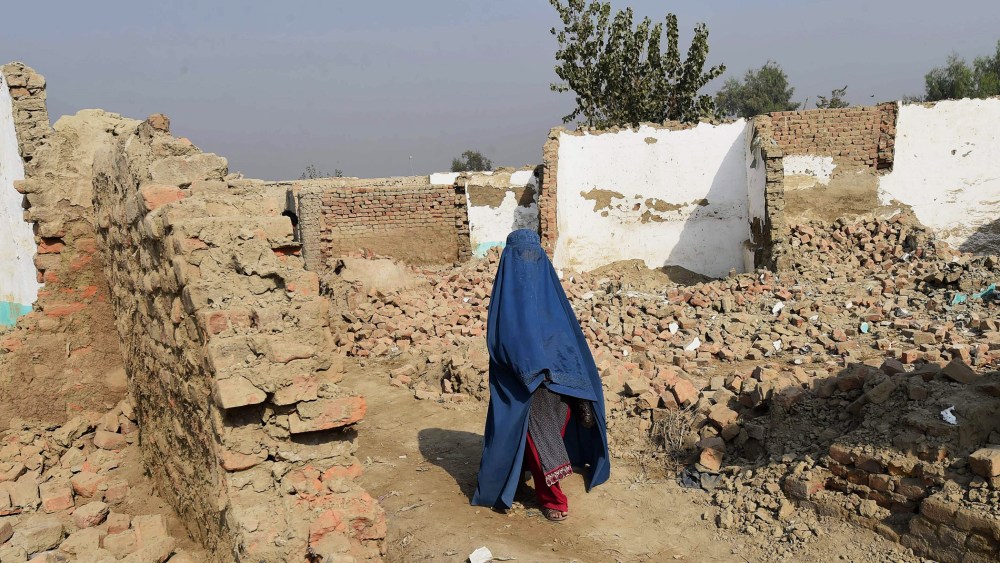 A Burqa-wearing Afghan refugee crosses in front of demolished houses in the Khazana refugees camp outskirts of Peshawar on Oct. 24, 2016. (Photo by A Majeed/AFP/Getty)