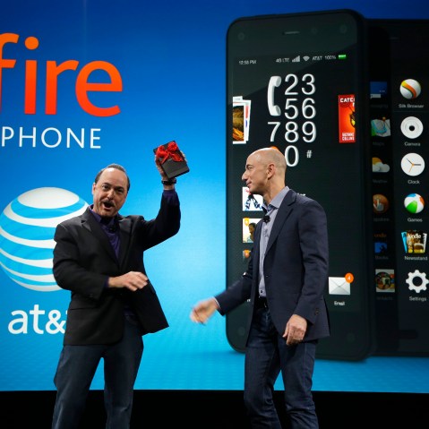 Ralph de la Vega, left, President and CEO of AT&T Mobility, accepts a gift from Amazon CEO Jeff Bezos, right, of what Bezos said is the first Amazon Fire Phone off the assembly line at the launch event for the new smartphone, Wednesday, June 18, 2014, in