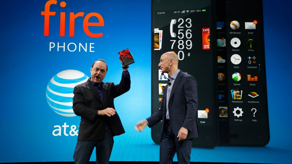 Ralph de la Vega, left, President and CEO of AT&T Mobility, accepts a gift from Amazon CEO Jeff Bezos, right, of what Bezos said is the first Amazon Fire Phone off the assembly line at the launch event for the new smartphone, Wednesday, June 18, 2014, in