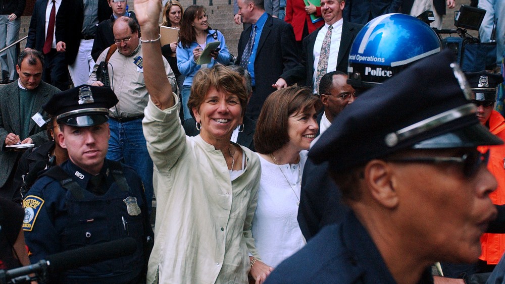 Hillary Goodridge holds up an envelope containing her marriage license as she leaves Boston City Hall with her partner Julie under a police escort in Boston, Monday May 17, 2004.
