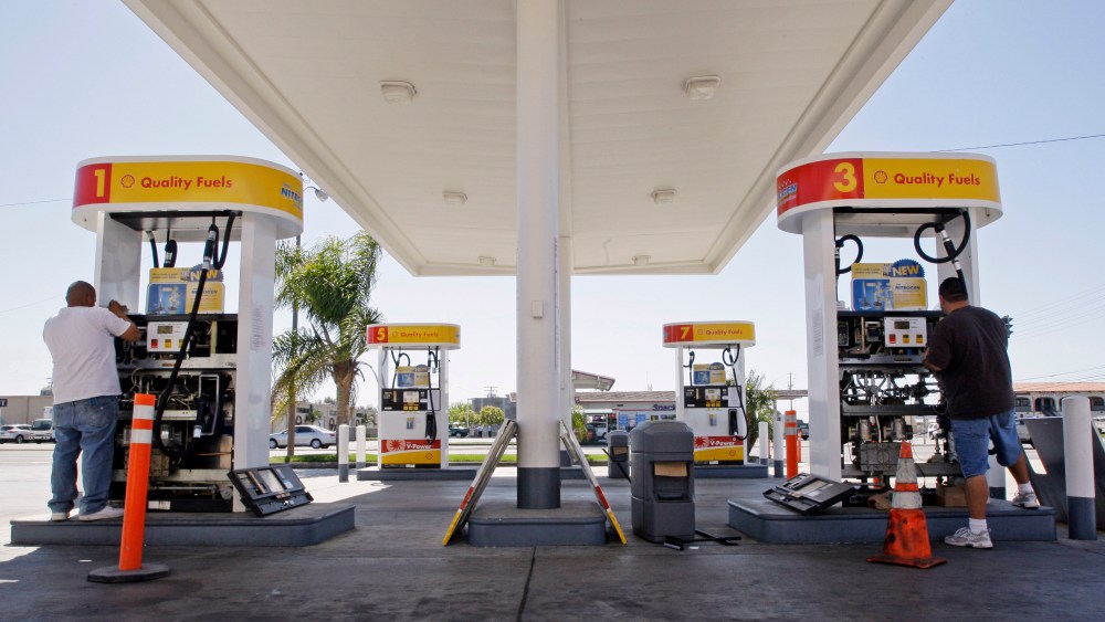 David Berri, right, and his assistant Adolfo Mendez install new valves and electronic controls to a pair of gas pumps at the Shell station Berri owns in Santa Ana, Calif., Saturday, March 28, 2009.  (AP Photo/Reed Saxon)