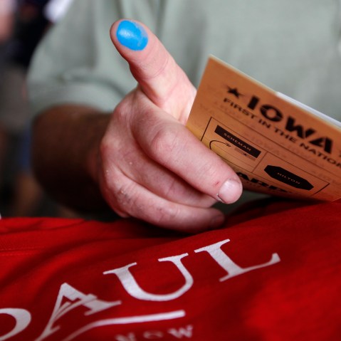 A voter who voted for Republican presidential candidate Rep. Ron Paul, R-Texas, shows his finger marked with indelible ink as he picks up a free shirt at the Republican Party's Straw Poll in Ames, Iowa, Aug. 13, 2011. (Photo by Charles Dharapak/AP)