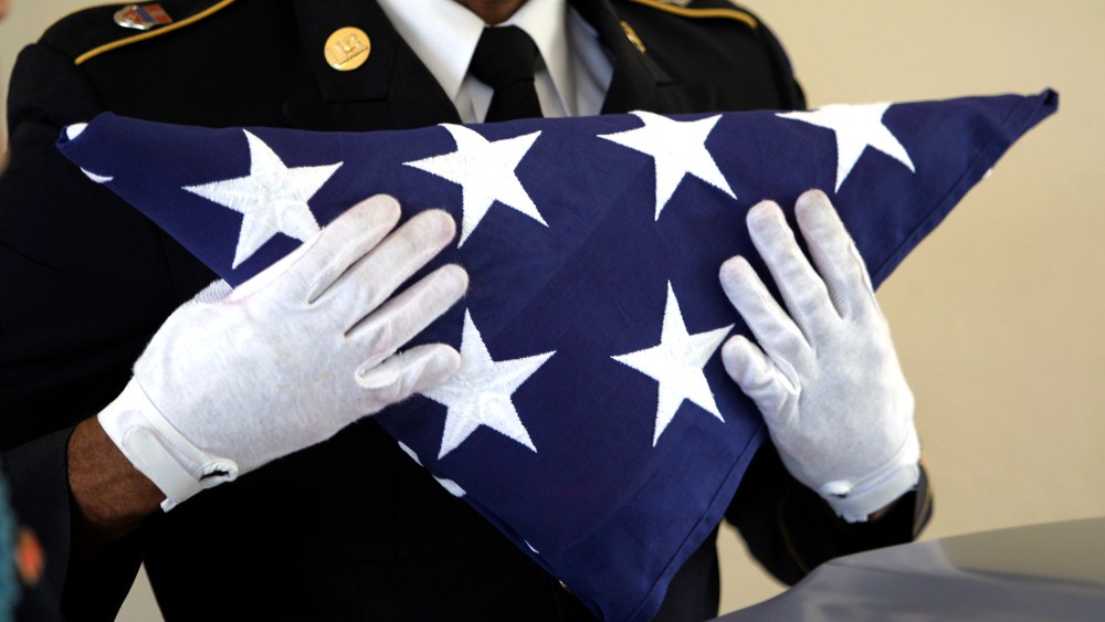 An Army National Guardsman, holds an American flag during a funeral.