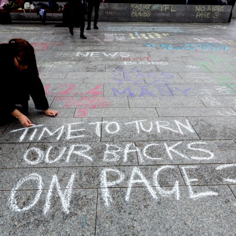 "No More Page 3" campaign write messages on the pavement to David Dinsmore, The Sun editor, outside the News UK head office 'No More Page Three' demonstration, on Nov. 16, 2014 in London, Britain. (Photo by Vickie Flores/Rex Features via AP)