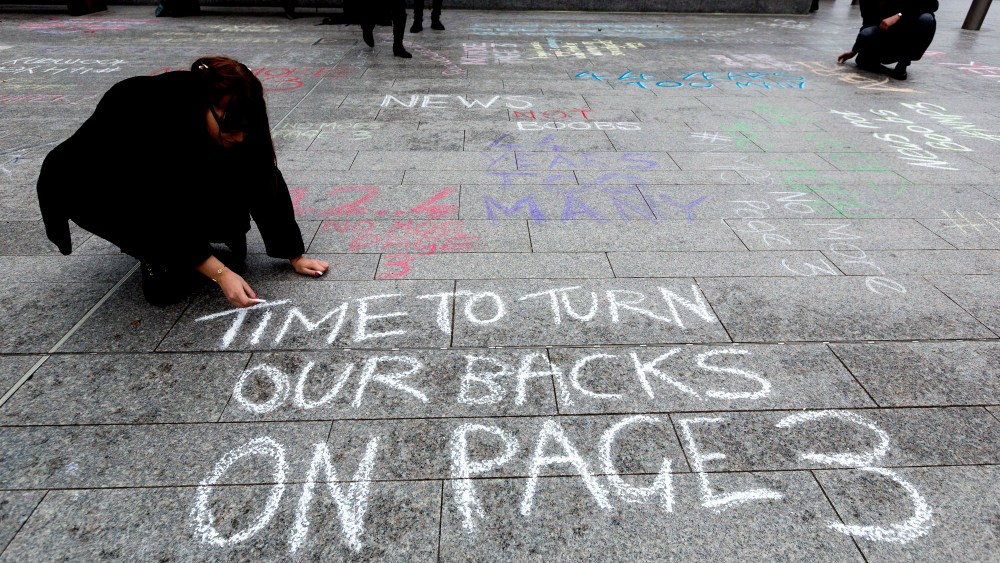 "No More Page 3" campaign write messages on the pavement to David Dinsmore, The Sun editor, outside the News UK head office 'No More Page Three' demonstration, on Nov. 16, 2014 in London, Britain. (Photo by Vickie Flores/Rex Features via AP)