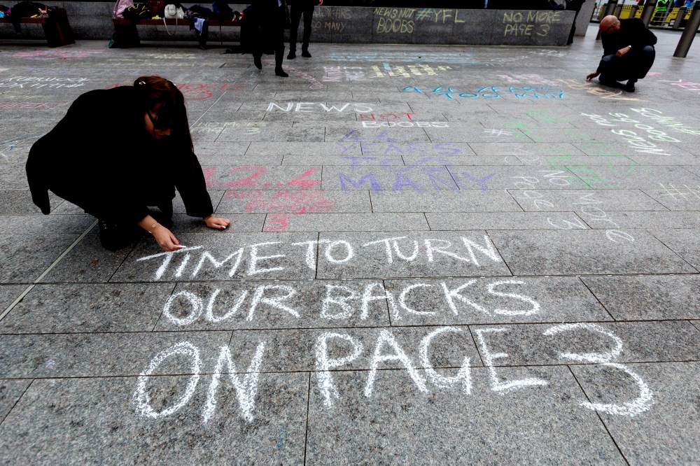 "No More Page 3" campaign write messages on the pavement to David Dinsmore, The Sun editor, outside the News UK head office 'No More Page Three' demonstration, on Nov. 16, 2014 in London, Britain. (Photo by Vickie Flores/Rex Features via AP)