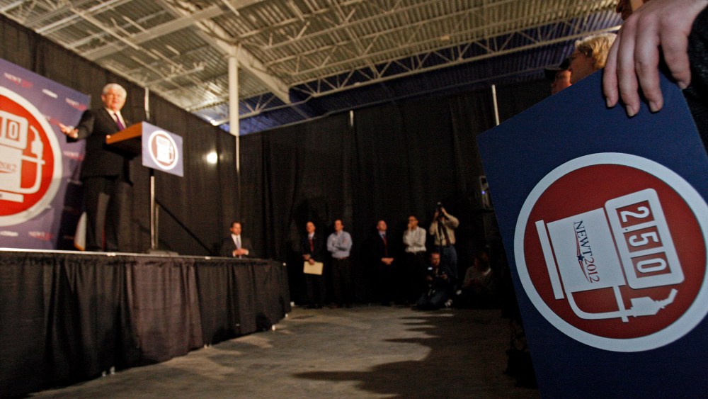 A supporter holds a campaign sign of Republican presidential candidate, former House Speaker Newt Gingrich, left, promoting his goal of $2.50 a gallon gas as he speaks at a rally in Brandon, Miss., Sunday, March 11, 2012.