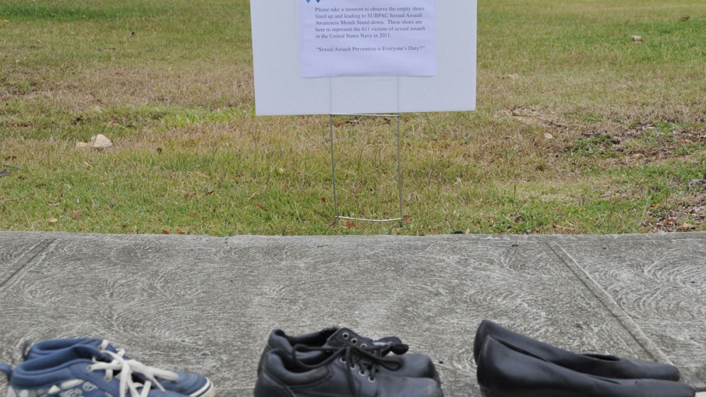 A Friday April 6, 2012 photo provided by the US Navy shows a sign that is displayed describing the 611 pairs of shoes lining the sidewalk in front of Sharkey Theater before a sexual assault event at Joint Base Pearl Harbor-Hickam in Hawaii. The shoes...