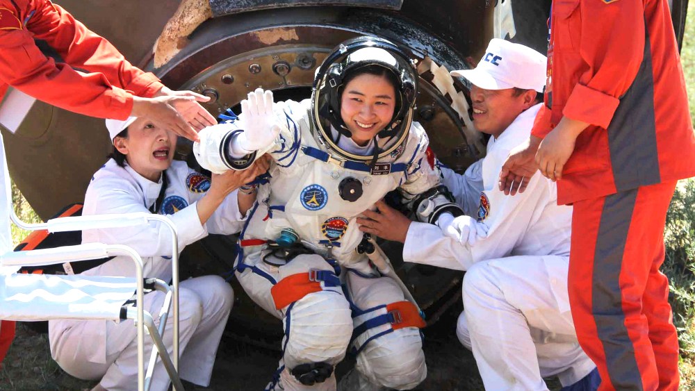 In this photo released by China's Xinhua news agency, China's first female astronaut Liu Yang waves as she comes out of the re-entry capsule of Shenzhou-9 spacecraft in Siziwang Banner of north China's Inner Mongolia Autonomous Region, June 29, 2012.