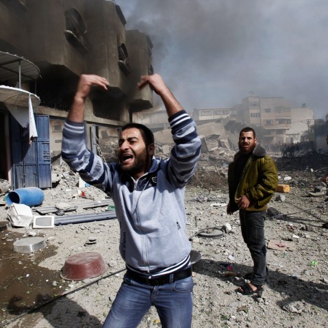 Palestinians call for help as they stand next to a damaged building after an Israeli air strike in Gaza City on Sunday. (AP Photo/Adel Hana)