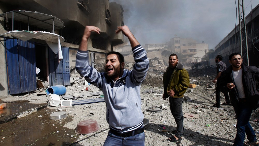 Palestinians call for help as they stand next to a damaged building after an Israeli air strike in Gaza City on Sunday. (AP Photo/Adel Hana)