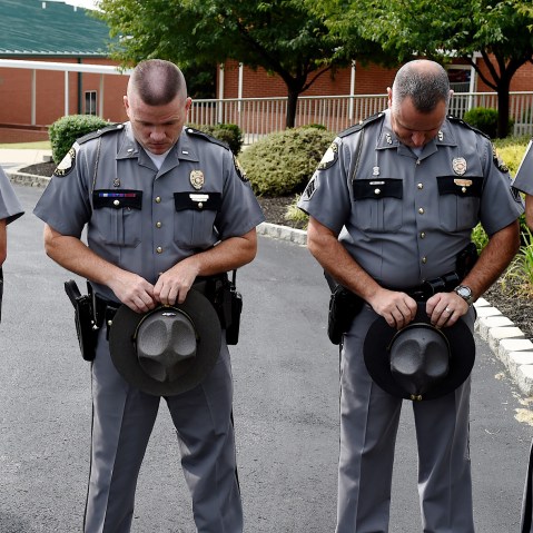 Kentucky State Troopers, from left, Eric Dilback, Lonnie Bell, Chris McKee, and Sean McKinney bow in prayer during a road renaming ceremony in memory of Chase Trent in Zion, Ky., Aug. 29, 2015. (Photo by Darrin Phegley/The Gleane/AP)