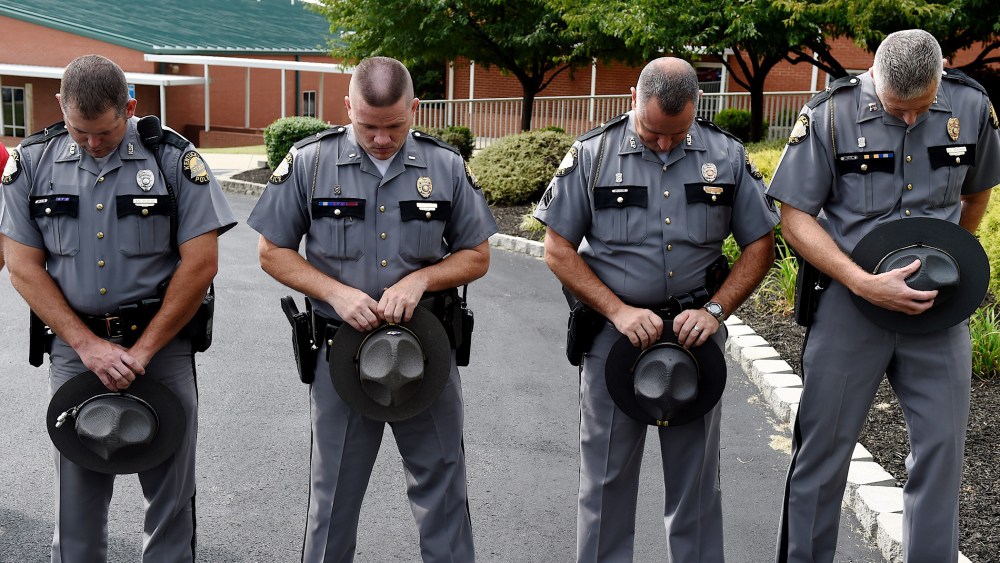 Kentucky State Troopers, from left, Eric Dilback, Lonnie Bell, Chris McKee, and Sean McKinney bow in prayer during a road renaming ceremony in memory of Chase Trent in Zion, Ky., Aug. 29, 2015. (Photo by Darrin Phegley/The Gleane/AP)