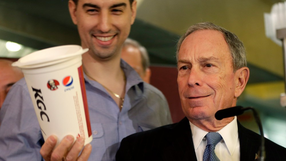 New York City Mayor Michael Bloomberg looks at a 64oz cup, as  Lucky's Cafe owner Greg Anagnostopoulos, left, stands behind him, during a news conference at the cafe in New York, Tuesday, March 12, 2013.  (AP Photo/Seth Wenig)