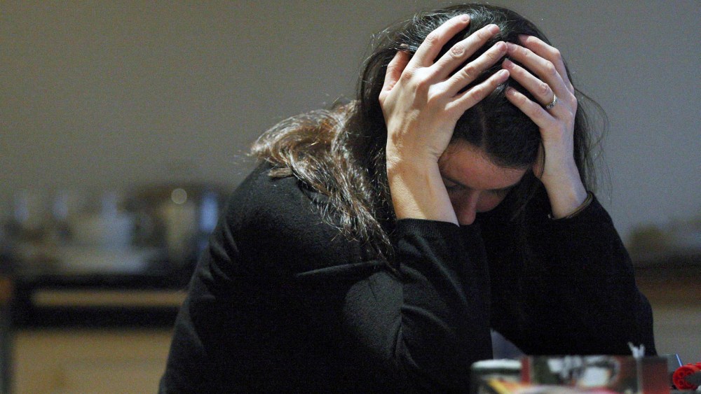 A posed woman with her head in her hands for a domestic violence awareness campaign. (Photo by David Cheskin/PA Wire/AP)