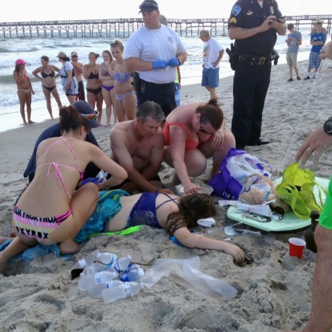 Emergency responders assist a teenage girl at the scene of a shark attack in Oak Island, N.C., June 14, 2015. (Photo by Steve Bouser/The Pilot, Southern Pines, N.C./AP)