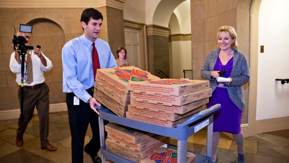 An aide brings a cart stacked with pizza to the office of Speaker of the House John Boehner, as movement toward ending the government shutdown was suddenly halted, at the Capitol in Washington, Tuesday night, Oct. 15, 2013.