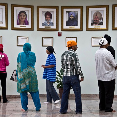 Visitors look at a memorial near the entrance of the Sikh Temple of Wisconsin Wednesday, July 31, 2013, in Oak Creek, Wis. Twelve months ago a white supremacist shot and killed six temple members, and the survivors plan to mark the one-year anniversary...