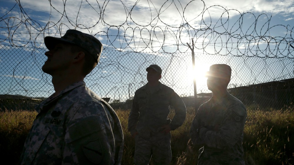 Military personnel walk in the now abandoned Camp X-Ray at Guantanamo Bay Naval Base, Cuba, Nov. 21, 2013.