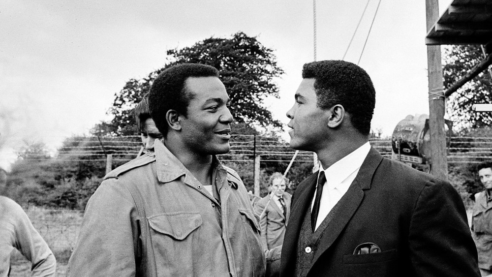 In this Aug. 5, 1966 photo, heavyweight boxer Muhammad Ali, right, visits Cleveland Browns running back and actor Jim Brown on the film set of "The Dirty Dozen" at Morkyate, Bedfordshire, England.